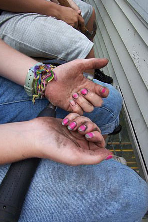 Dirty hands with pink fingernails.
