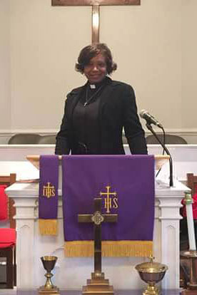 The Rev. Jackie Ford poses in the pulpit of her church. 