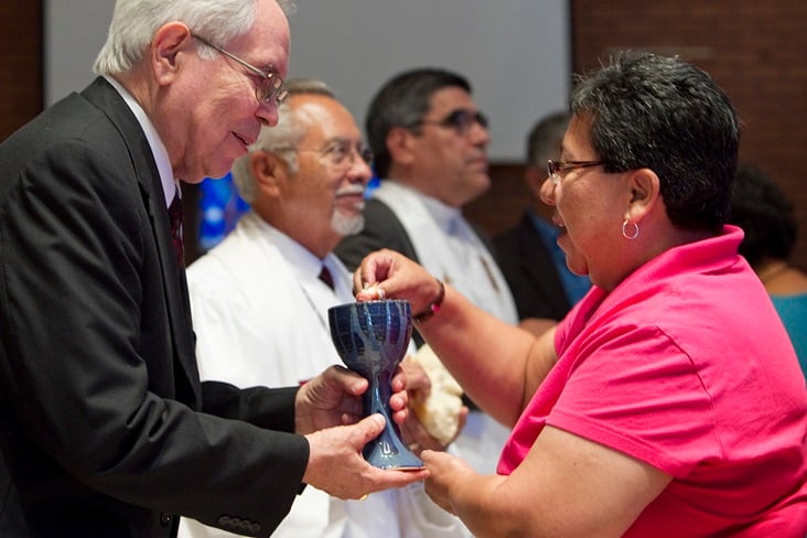 marcha-2011-15 The Rev. Noé Gonzales (left) offers Holy Communion to Nohemi Ramirez during worship in El Paso, Texas. Photo by Mike DuBose, United Methodist Communications.