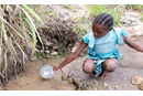 A young girl patiently collects water for her family from a slow-running spring. Collecting water from the source and treating it with chlorine tablets decreases the spread of cholera and other waterborne diseases. Photo: Courtesy of North Katanga UMC Health Board.