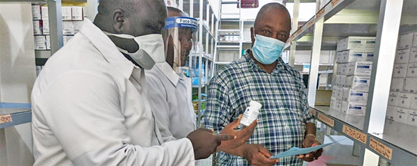 Allen S.D. Zomonway (right), a registered nurse and Ganta United Methodist Hospital administrator, reviews drug stocks with staff in the hospital pharmacy. During the pandemic, the Africa University graduate ensures that all hospital employees wear masks and take other necessary precautions. Photo courtesy of Africa University.