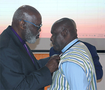 Retired Bishop Warner H. Brown (left), interim bishop of the Sierra Leone Area, bestows the episcopal pin on the Rev. James Boye-Caulker after he was elected bishop. Boye-Caulker, who has served as district superintendent of Sierra Leone’s Western District since 2016, was the second bishop elected. Photo by Eveline Chikwanah, UM News.