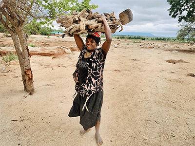 Rebecca Navaya carries firewood to her family’s temporary home in Nkhulambe, Malawi, near the border with Mozambique. Navaya is among survivors of Cyclone Freddy who are rebuilding their lives with support from the United Methodist Committee on Relief. Photo by Francis Nkhoma, UM News.